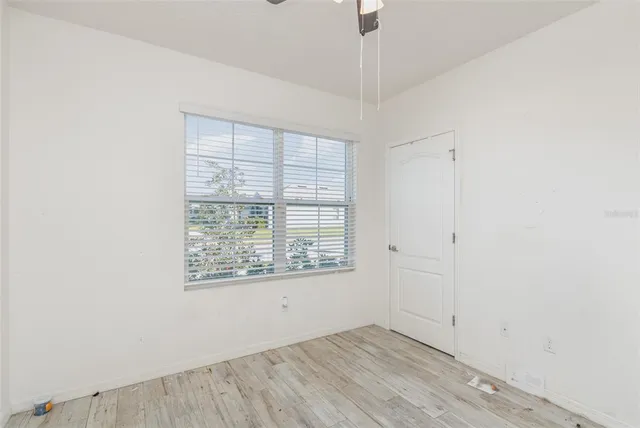 an empty room with wooden floor cabinet and windows