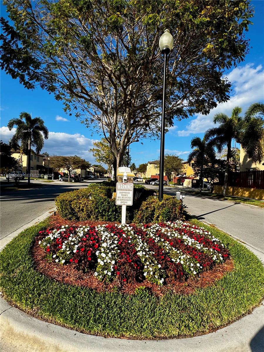 9219 Southwest 227th Street, Unit 9 Cutler Bay, FL 33190 - Photo 3 of 42 a view of a street with flower plants and bench next to a road