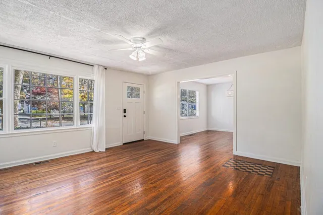 a view of an empty room with wooden floor and a window