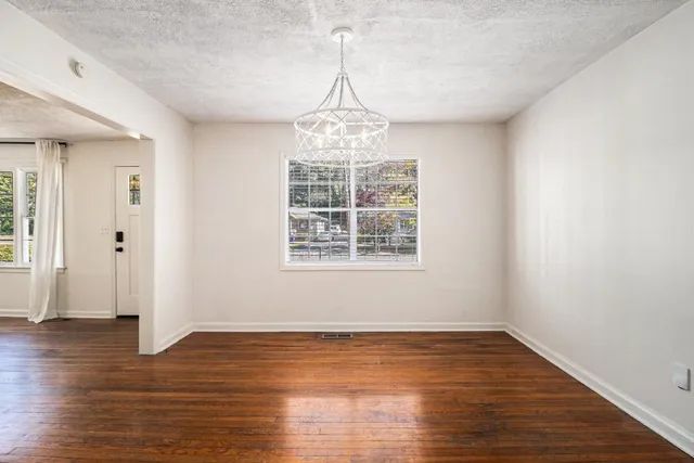 an empty room with wooden floor cabinet and windows