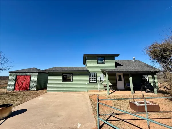 a view of a house with table and chairs under an umbrella with a barbeque grill and a small yard