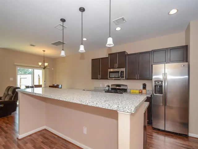 a kitchen with stainless steel appliances granite countertop a sink a refrigerator a stove a microwave and island