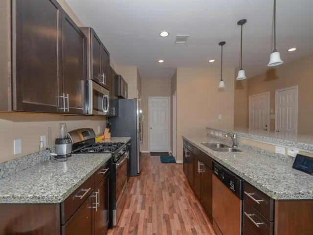 a kitchen with stainless steel appliances granite countertop a sink a stove and a wooden floors