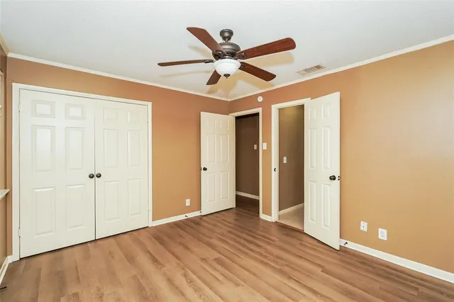 a view of an empty room with wooden floor and a ceiling fan