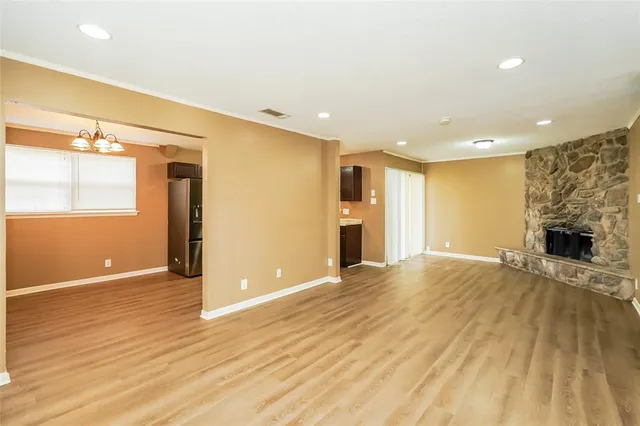 a view of an empty room with wooden floor and a fireplace