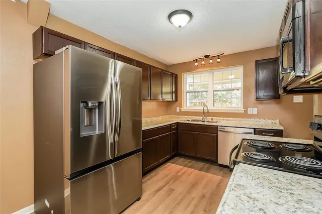 a kitchen with granite countertop a refrigerator stove and sink