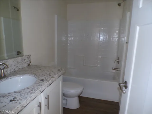 a bathroom with a granite countertop sink a toilet and shower