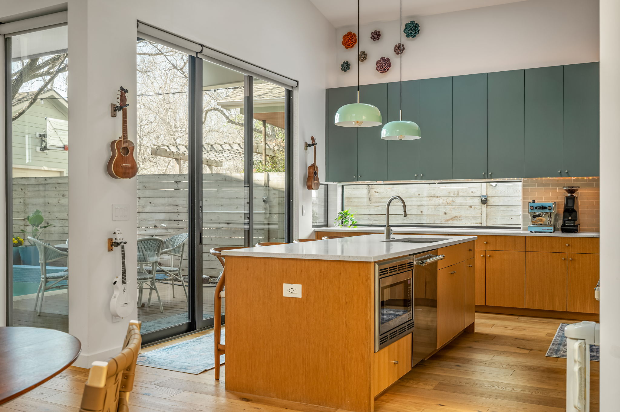 1811 Collier Street Austin, TX 78704 - Photo 6 of 40 Kitchen with light wood-style flooring, a center island with sink, light stone countertops, stainless steel appliances, and tasteful backsplash