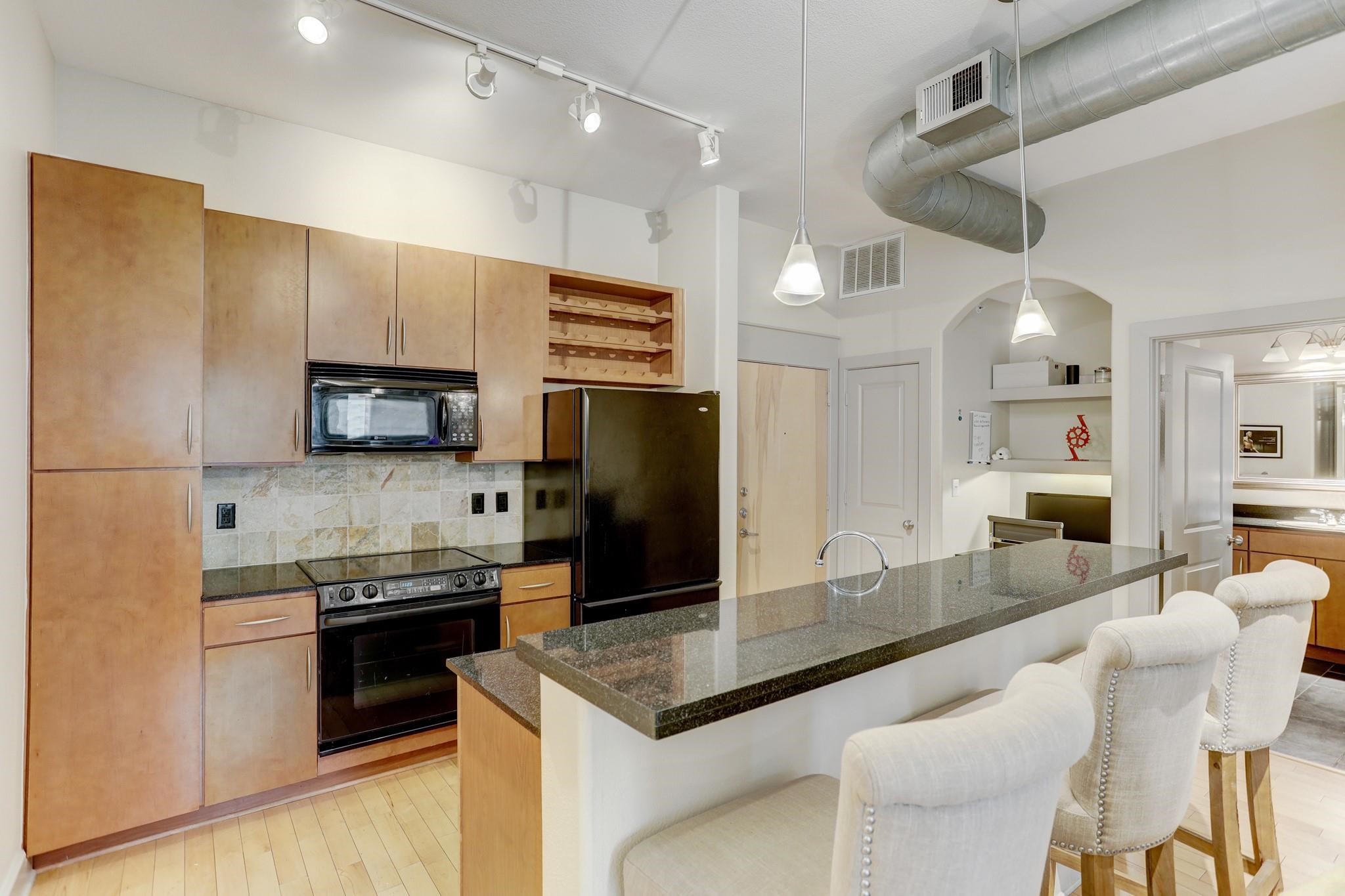 1901 Post Oak Boulevard, Unit 3502 Houston, TX 77056 - Photo 8 of 14 a kitchen with stainless steel appliances kitchen island granite countertop a refrigerator a stove a sink a dining table and chairs with wooden floor