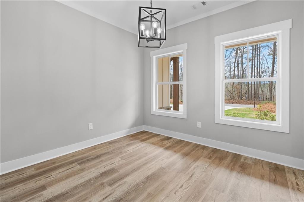 6093 Wayfarer Drive Villa Rica, GA 30180 - Photo 11 of 70 an empty room with wooden floor chandelier and windows