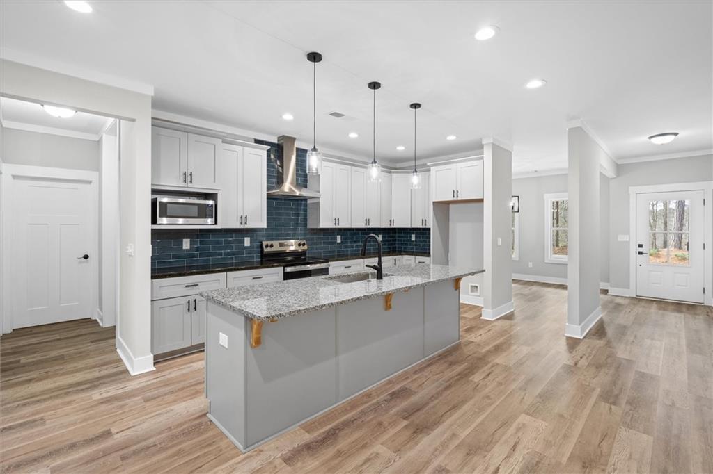 6093 Wayfarer Drive Villa Rica, GA 30180 - Photo 14 of 70 a large kitchen with stainless steel appliances kitchen island wooden floors wooden cabinets and view living room