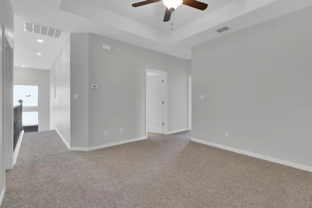 an empty room with a ceiling fan and carpet