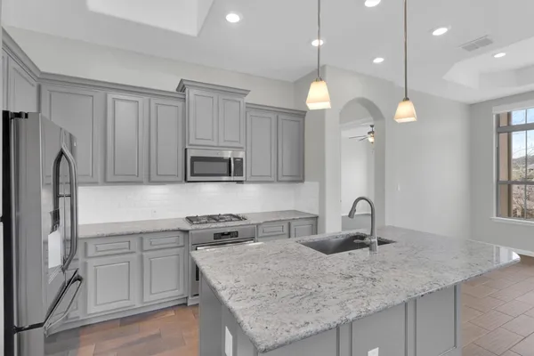 a kitchen with stainless steel appliances granite countertop a sink refrigerator and cabinets