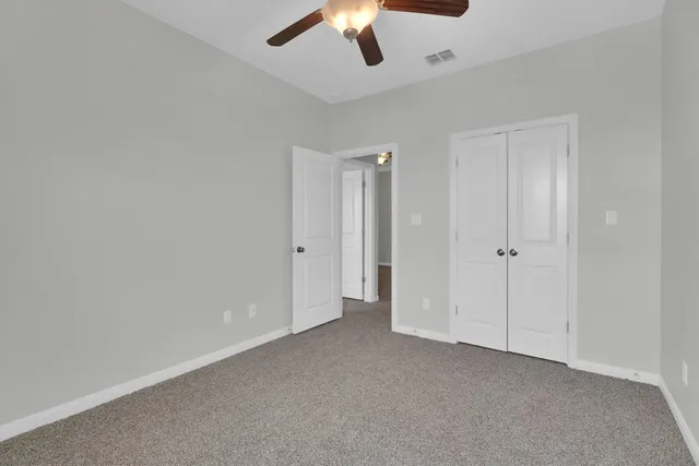 an empty room with closet and a ceiling fan