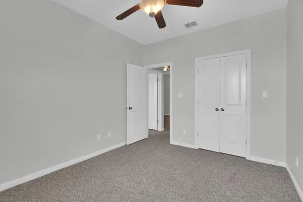 an empty room with windows and fan