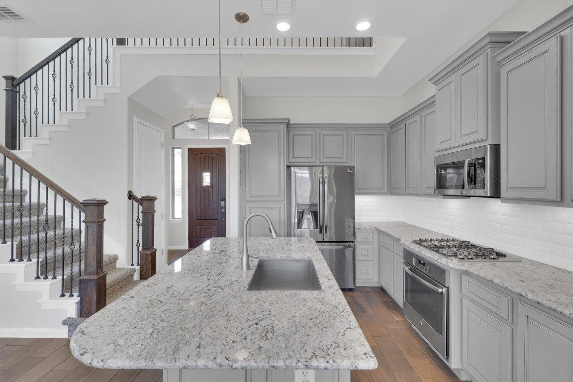 201 Cartwheel Bend, Unit 30 Austin, TX 78738 - Photo 4 of 40 a kitchen with stainless steel appliances kitchen island granite countertop a stove a sink dishwasher and a refrigerator with wooden floor