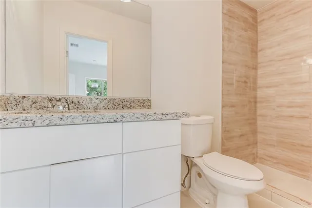 a bathroom with a granite countertop toilet sink and mirror