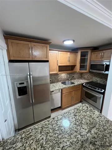 a kitchen with granite countertop a refrigerator and a stove top oven