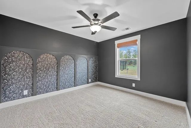 an empty room with ceiling fan and window
