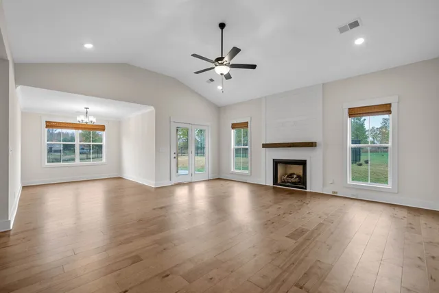 a view of an empty room with wooden floor fireplace and a window