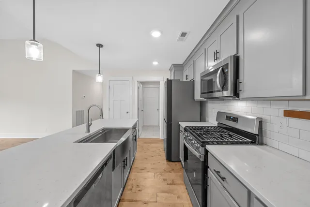 a kitchen with stainless steel appliances granite countertop a sink a stove and a refrigerator