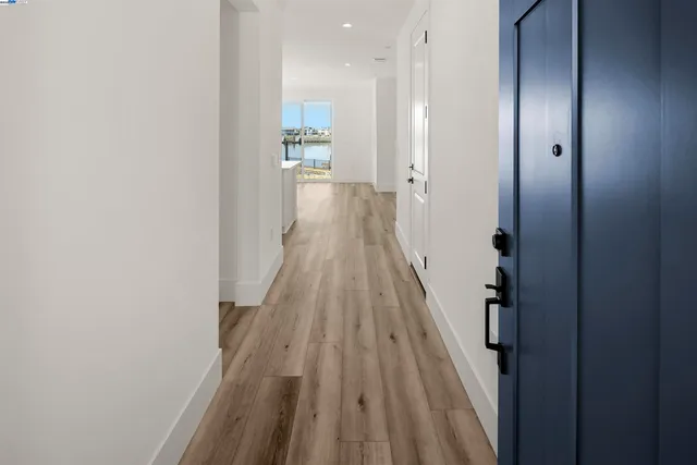 a view of a hallway with wooden floor and a bathroom