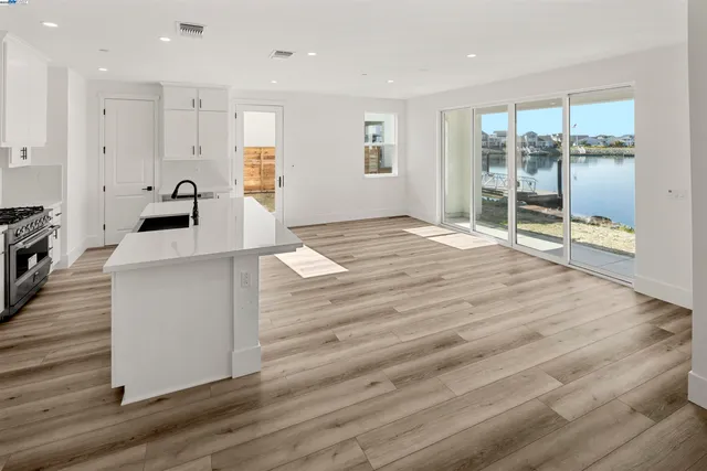 a large white kitchen with wooden floors and wide window