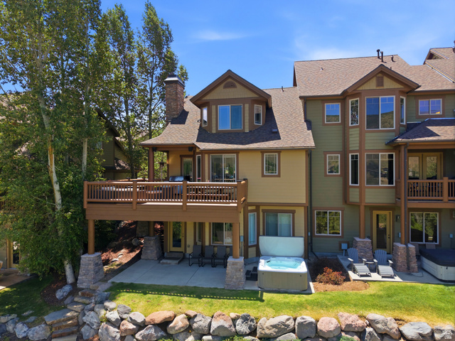 3148 Lower Saddleback Road Park City, UT 84098 - Photo 6 of 67 Multi-level townhouse exterior featuring a wood-finish deck, stone retaining wall, and a ground-level patio with a spa