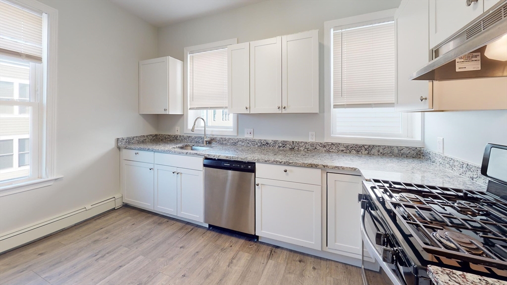 108 Boston Street, Unit 2 Boston, MA 02125 - Photo 1 of 10 a kitchen with granite countertop white cabinets and a stove top oven