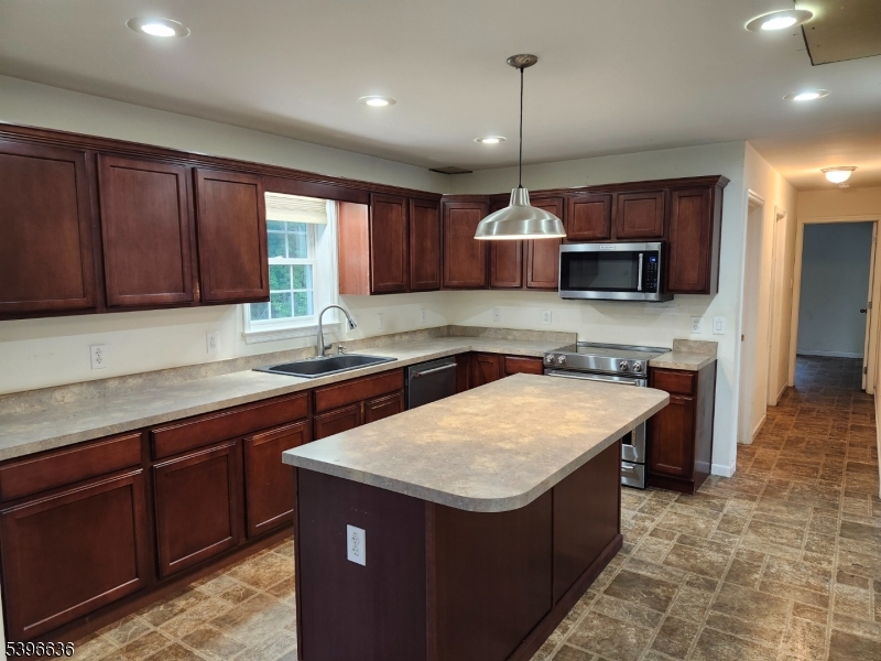 128 Big Piece Road Fairfield, NJ 07004 - Photo 6 of 22 a kitchen with kitchen island granite countertop wooden cabinets a stove a sink and a center island