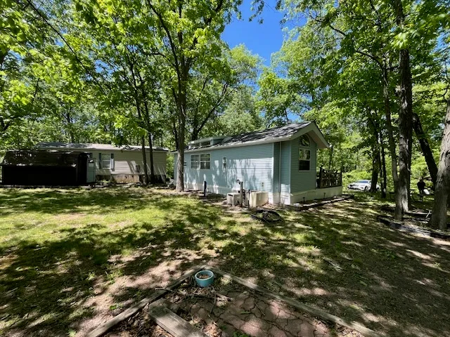 a backyard of a house with table and chairs under an umbrella