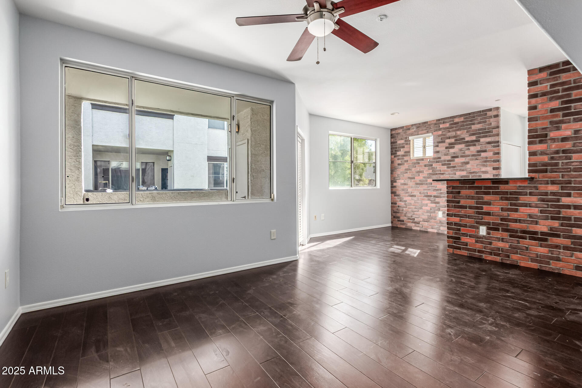 3302 North 7th Street, Unit 225 Phoenix, AZ 85014 - Photo 2 of 23 an empty room with wooden floor fan and windows