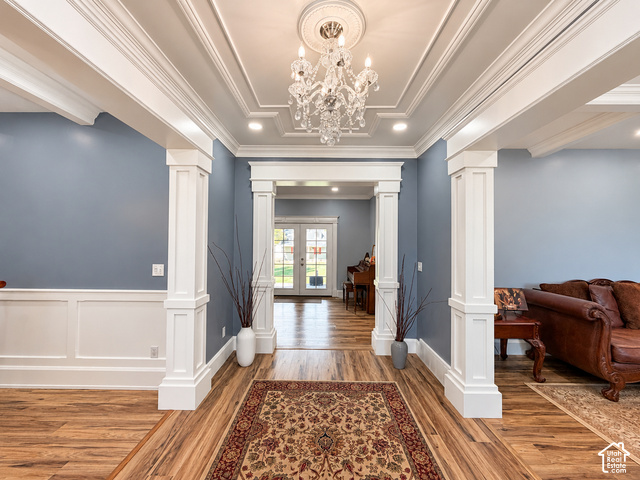 1750 West 4100 North Helper, UT 84526 - Photo 3 of 50 Elegant foyer showcasing coffered ceiling detail with crystal chandelier, white wainscoting and pilasters flanking the entry, blue-gray upper walls, and rich wood-finish flooring throughout
