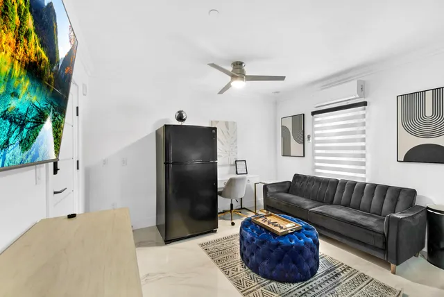 a living room with furniture and a refrigerator