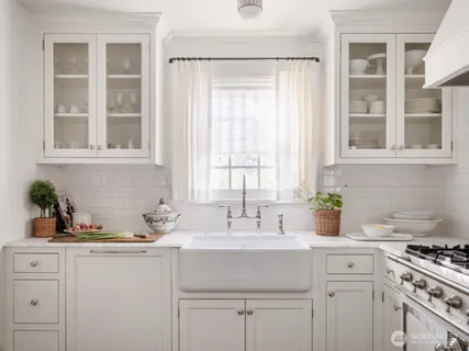 a kitchen with stainless steel appliances a sink a stove and white cabinets