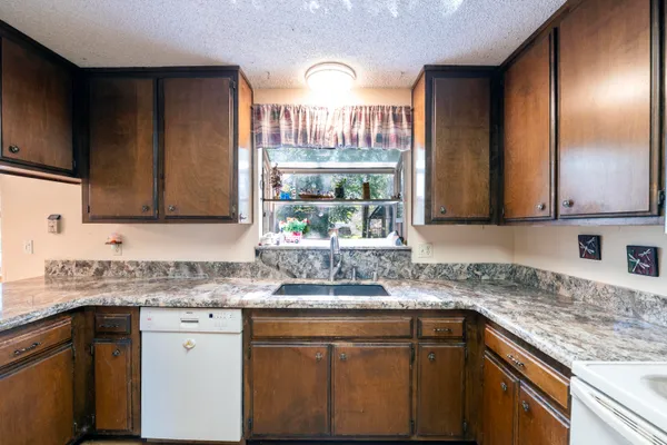 a kitchen with granite countertop a sink stainless steel appliances and cabinets