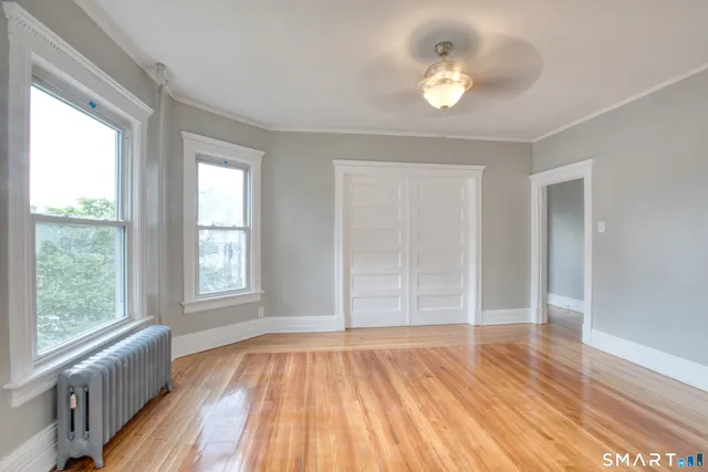 an empty room with wooden floor and windows