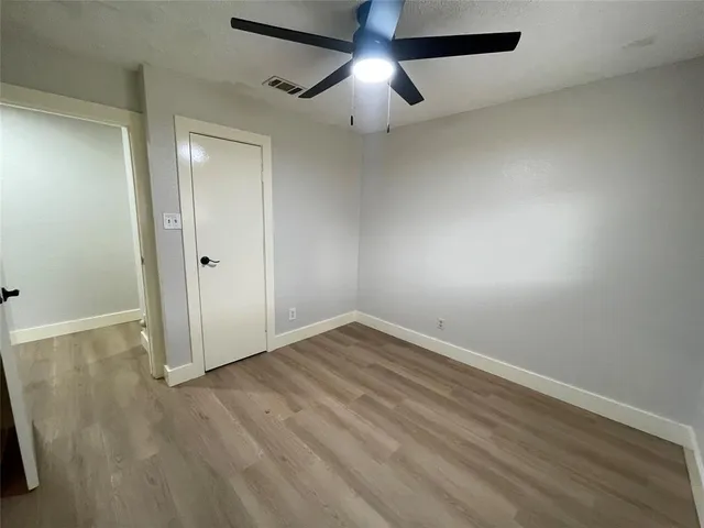 an empty room with wooden floor fan and window