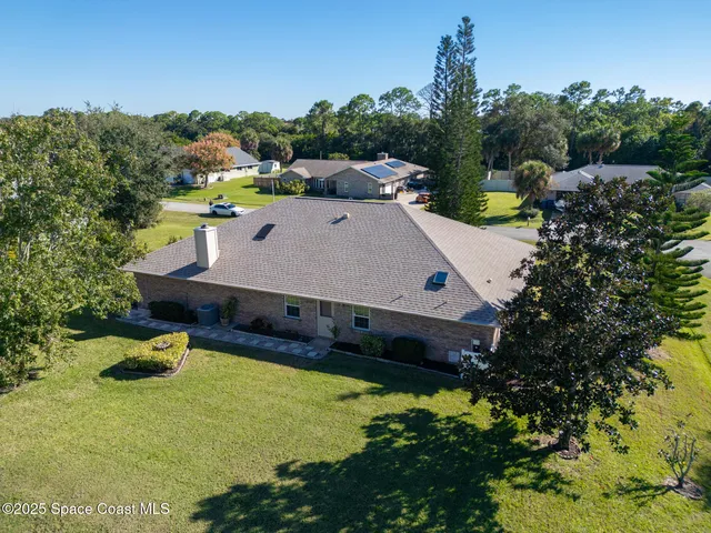 an aerial view of residential houses with outdoor space and trees