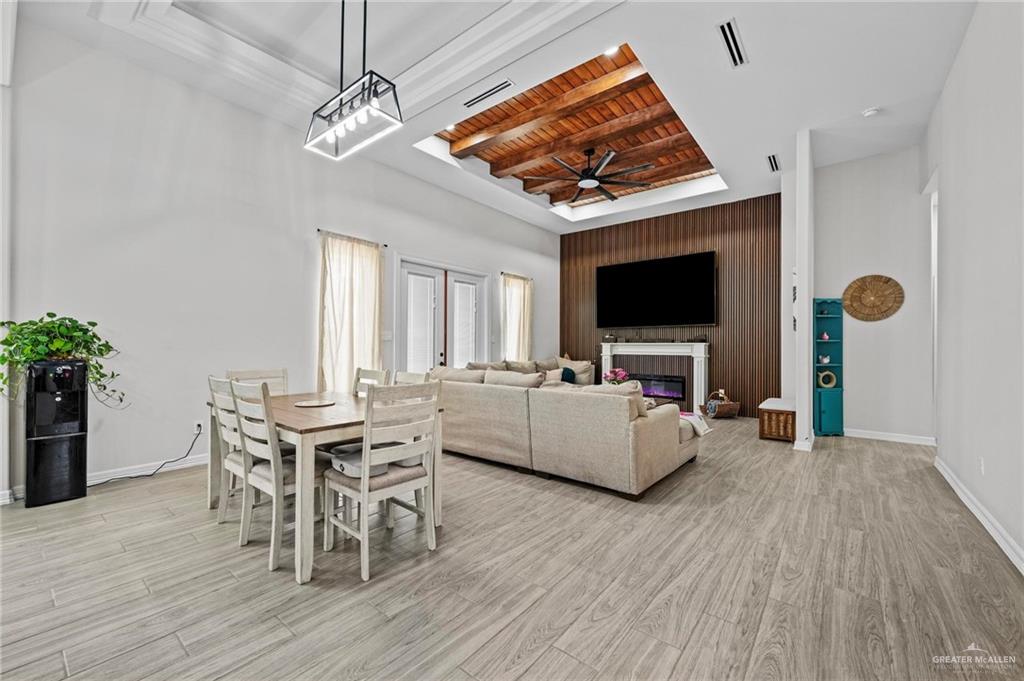 23247 Uresti Road Edinburg, TX 78542 - Photo 3 of 18 Wood-finish flooring, high vaulted ceilings, tray ceiling with wood paneling, contemporary ceiling fan, and built-in fireplace