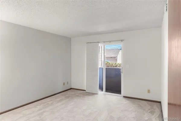 a view of an empty room with closet and a window