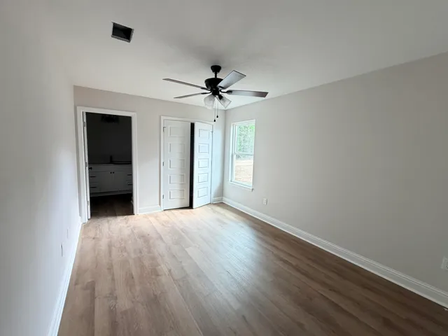 a view of empty room with wooden floor and fan