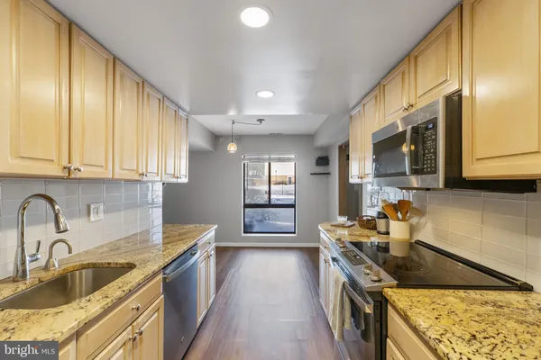 a kitchen with stainless steel appliances granite countertop a sink a stove and a wooden cabinets