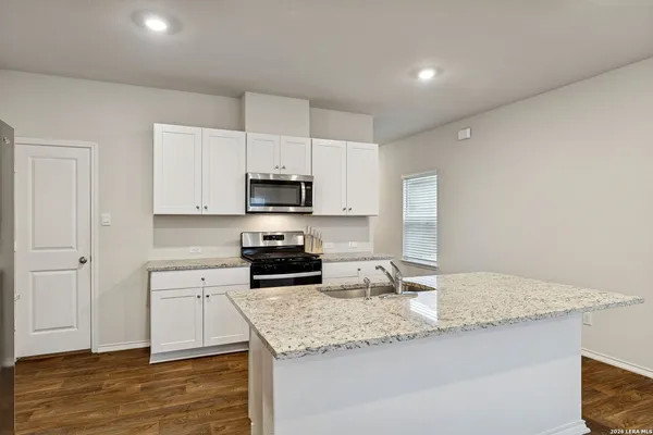 a kitchen with granite countertop a sink stove and refrigerator