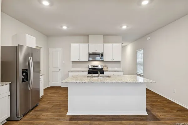 a large kitchen with stainless steel appliances granite countertop a stove a refrigerator a sink and dishwasher with wooden floor