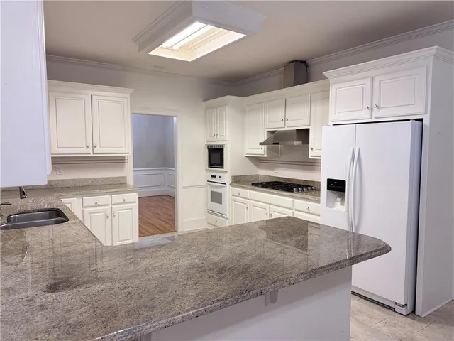 a kitchen with granite countertop a refrigerator and a sink