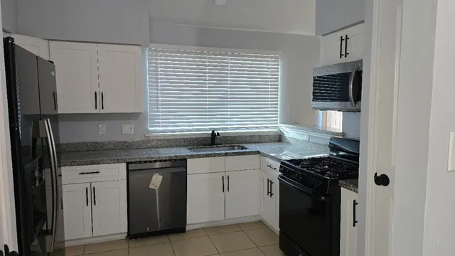 a kitchen with granite countertop stainless steel appliances a sink stove and cabinets