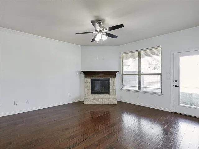 a view of an empty room with wooden floor fireplace and a window
