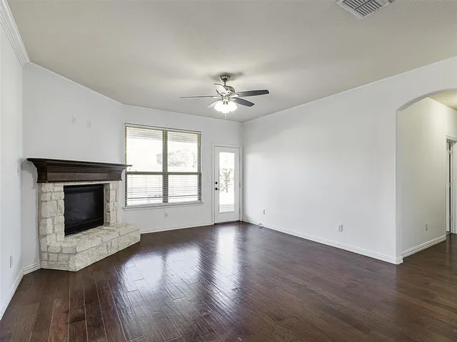 an empty room with wooden floor fireplace and windows