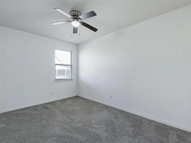an empty room with a chandelier fan and windows